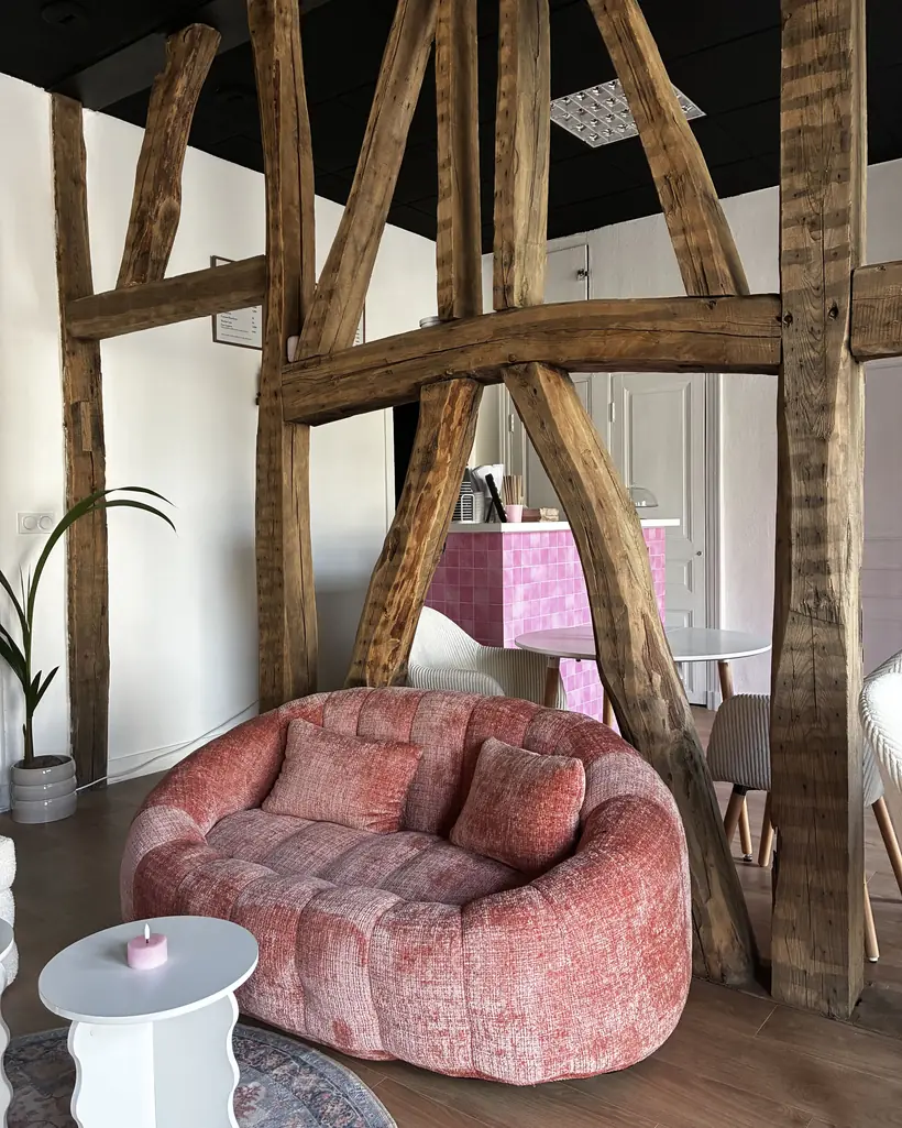 Le salon du Quartier Littéraire à Rennes : canapé terracotta sous les colombages anciens, comptoir carrelé rose en arrière-plan