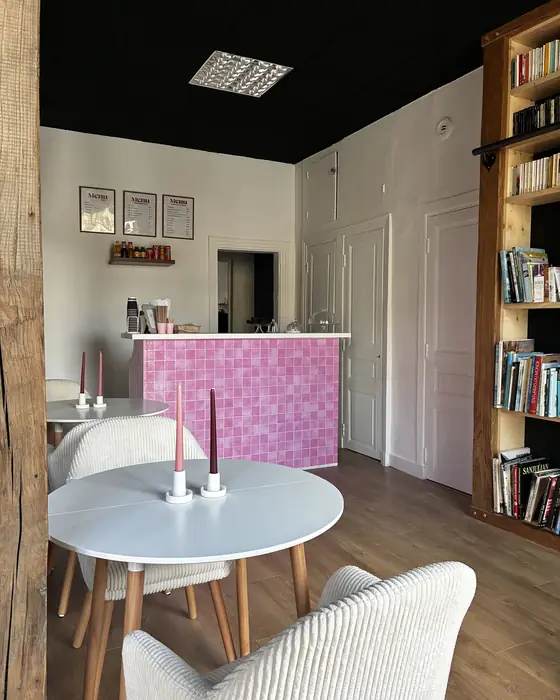 Le comptoir du café, carrelage rose et menus encadrés, avec les tables du salon