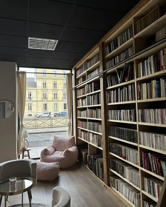 Coin lecture près de la vitrine, pouf rose et rayonnages de livres d'occasion